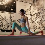 woman doing yoga beside mural wall