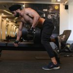 man in black pants and black nike shoes sitting on black bench press