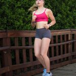 Young woman jogging on a wooden path outdoors.