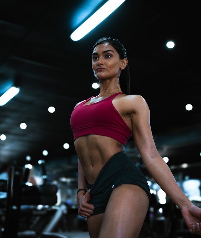 a woman in a red top and green skirt in a gym