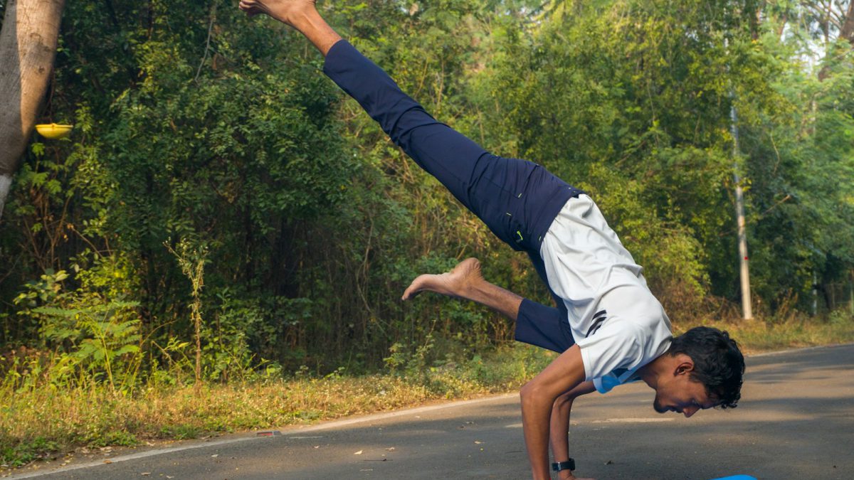 A man doing a handstand on a blue mat